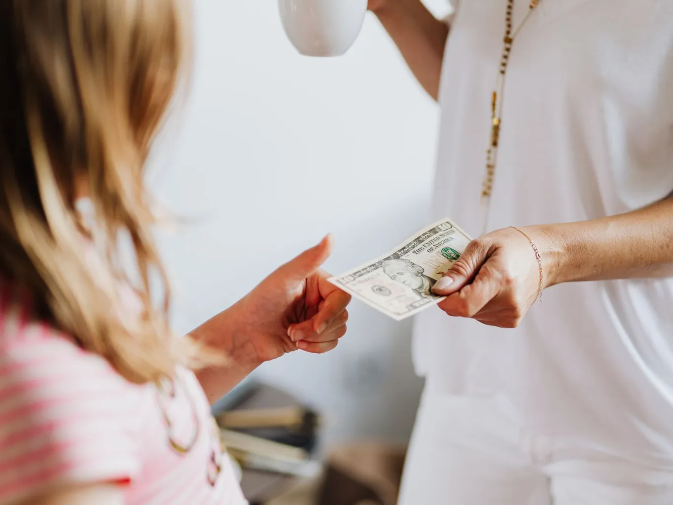 An older woman handing a ten dollar bill to a young girl